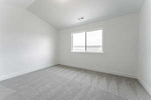Unfurnished room featuring baseboards, visible vents, light colored carpet, and vaulted ceiling