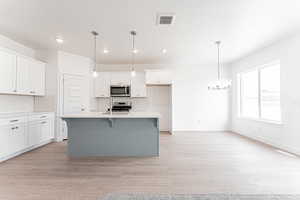 Kitchen featuring recessed lighting, a sink, a chandelier, stainless steel appliances, and white cabinets