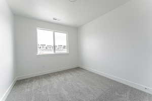 Carpeted spare room with a textured ceiling, visible vents, and baseboards