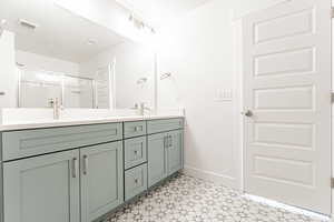 Bathroom with tile patterned floors, double vanity, a sink, baseboards, and visible vents