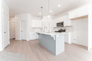 Kitchen with a sink, light wood-type flooring, a breakfast bar, backsplash, and appliances with stainless steel finishes