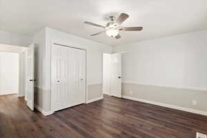 Unfurnished bedroom with a closet, ceiling fan, and dark wood-type flooring