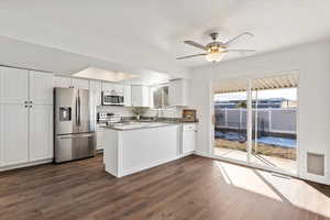 Kitchen with dark wood-type flooring, white cabinetry, dark stone countertops, and stainless steel appliances