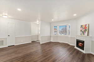 Unfurnished living room featuring dark wood-type flooring