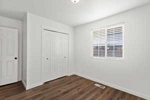 Unfurnished bedroom with a closet and dark wood-type flooring