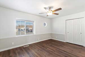 Unfurnished bedroom featuring a closet, ceiling fan, and dark wood-type flooring