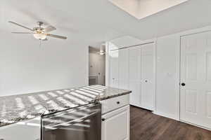 Kitchen featuring white cabinetry, dark hardwood / wood-style floors, ceiling fan, and light stone counters