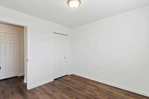 Unfurnished bedroom with dark hardwood / wood-style floors and a closet