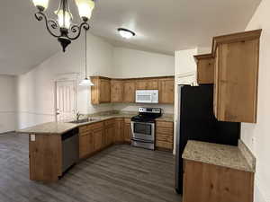 Kitchen featuring sink, high vaulted ceiling, pendant lighting, dark hardwood / wood-style flooring, and stainless steel appliances