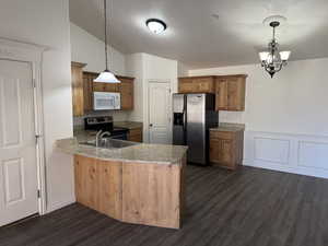 Kitchen with pendant lighting, appliances with stainless steel finishes, and kitchen peninsula