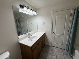 Full bathroom featuring toilet, vanity, shower / tub combo with curtain, and tile patterned flooring