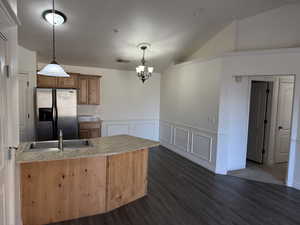 Kitchen with sink, pendant lighting, stainless steel fridge with ice dispenser, and lofted ceiling