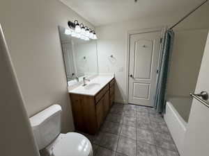 Full bathroom with vanity, toilet, tile patterned floors, and shower / bath combo with shower curtain