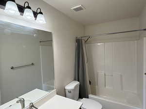 Full bathroom featuring toilet, shower / tub combo with curtain, and vanity