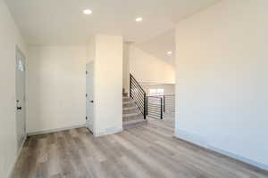 Spare room with vaulted ceiling and light hardwood / wood-style floors