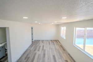 Unfurnished room featuring light wood-type flooring and a textured ceiling