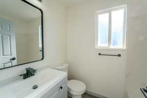 Bathroom featuring vanity, toilet, and a healthy amount of sunlight