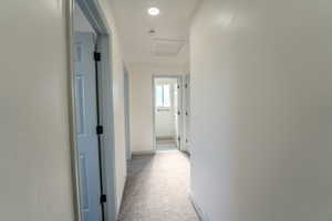 Hallway featuring light colored carpet