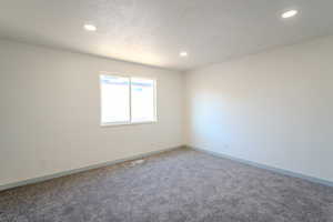 Carpeted empty room with a textured ceiling