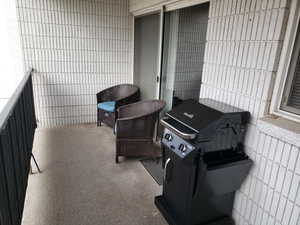 View of patio with a balcony and area for grilling