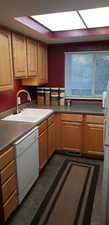 Kitchen featuring sink, white appliances, and a skylight