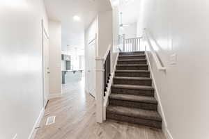 Stairs featuring wood finished floors, visible vents, a ceiling fan, and baseboards