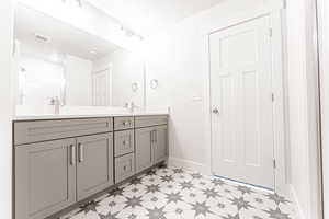 Bathroom with baseboards, visible vents, double vanity, and a sink