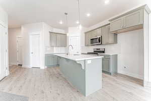 Kitchen featuring gray cabinets, stainless steel appliances, decorative backsplash, and a sink