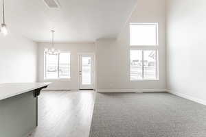 Unfurnished dining area featuring visible vents, a notable chandelier, a textured ceiling, and plenty of natural light