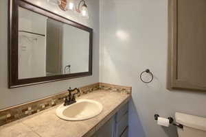 Bathroom with toilet, tasteful backsplash, walk in shower, and vanity