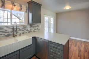 Kitchen featuring decorative backsplash, kitchen peninsula, hanging light fixtures, and stainless steel dishwasher