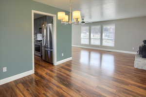 Interior space featuring a textured ceiling, a notable chandelier, and dark hardwood / wood-style flooring