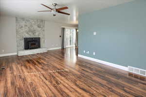 Unfurnished living room featuring ceiling fan and dark wood-type flooring