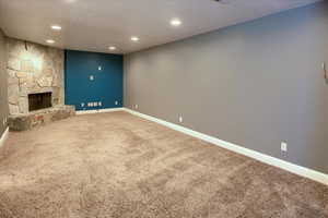 Unfurnished living room with carpet flooring and a stone fireplace