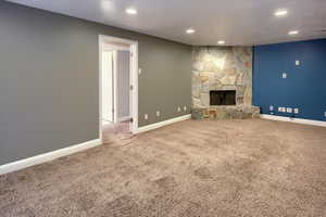 Unfurnished living room with carpet flooring and a stone fireplace