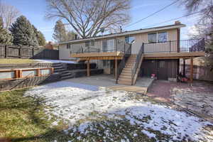 Snow covered back of property with a patio area and a wooden deck