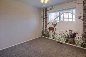 Carpeted spare room featuring ceiling fan