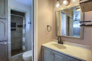 Bathroom with toilet, tile patterned flooring, walk in shower, and vanity