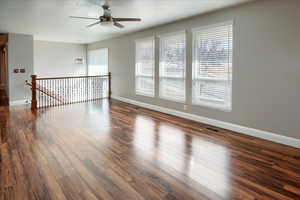 Unfurnished room with ceiling fan and dark hardwood / wood-style flooring