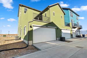 View of home's exterior with a balcony, central AC, and a garage