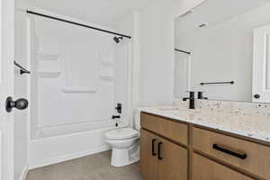 Full bathroom featuring toilet, washtub / shower combination, tile patterned floors, and vanity