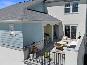 Back of house featuring an outdoor living space, a balcony, and a water view