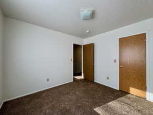 Unfurnished bedroom featuring a closet and dark carpet