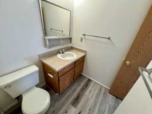 Bathroom with hardwood / wood-style floors, toilet, and vanity