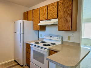 Kitchen with kitchen peninsula, light hardwood / wood-style flooring, and white electric range