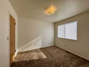 Empty room with a textured ceiling and carpet