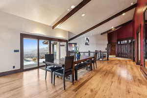 Dining room featuring a mountain view, high vaulted ceiling, light wood-type flooring, and beam ceiling
