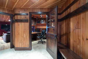 Office space with wooden walls, built in desk, and wood ceiling