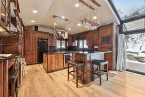 Kitchen with pendant lighting, a center island, wine cooler, black fridge, and vaulted ceiling