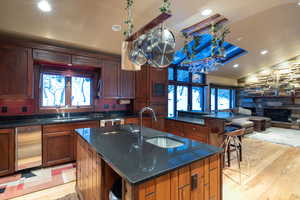 Kitchen with sink, a center island with sink, lofted ceiling, and light wood-type flooring